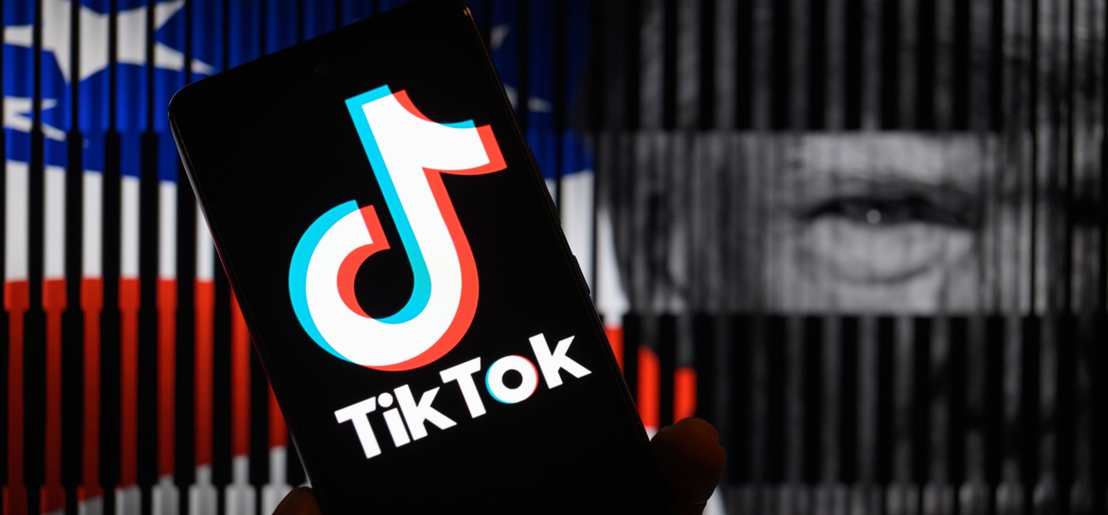 TikTok logo is being displayed on a mobile screen, in front of a photo illustration featuring the American flag and Trump.